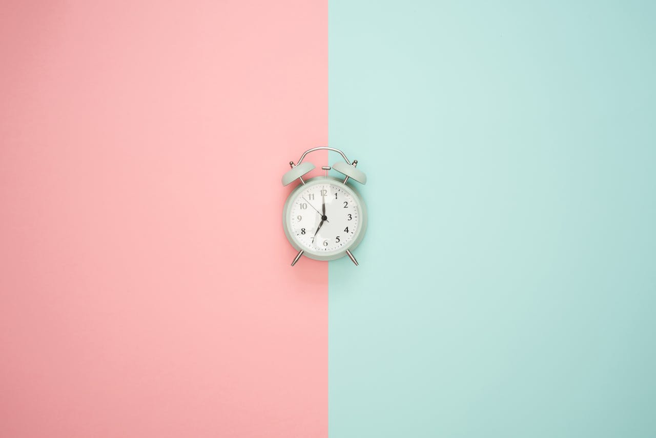 why-choose-us A vintage round clock on a split pastel pink and blue background.