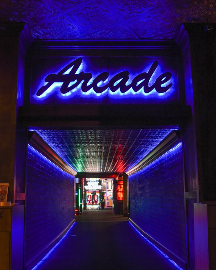 gallery-6 Vibrant neon light hallway leading to retro arcade gameplay area.