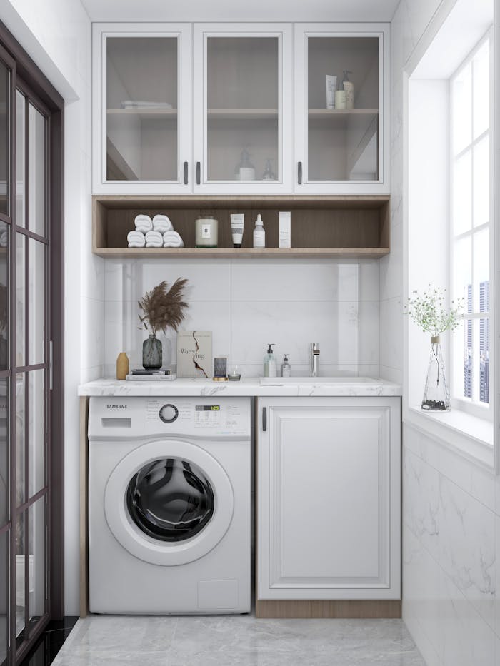 A sleek and bright laundry room featuring a washing machine, cabinets, and natural decor.